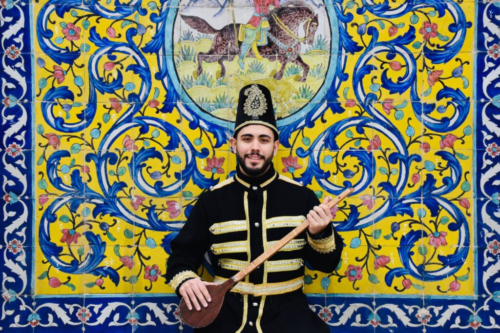 bel Iranien en tenue traditionnelle devant mosaïque 